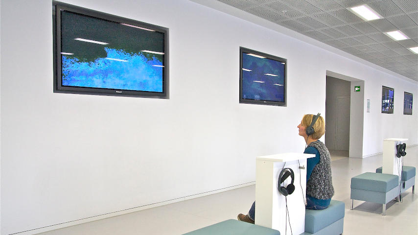 Besucherin betrachtet Ausstellung auf einem Monitor der Galerie b