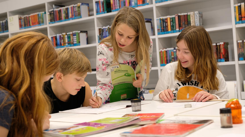 Besucher mit langen schwarzen Haaren trägt Kopfhörer vor Bücherregal